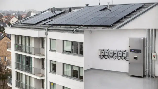 Mehrfamilienhaus mit Solaranlage auf dem Dach und Stromzählern für Mieterstrom