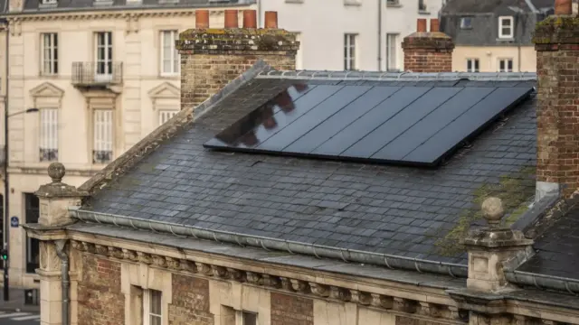 Dach eines historischen Gebäudes mit Solarmodulen auf einer rückwärtigen Fläche und Denkmalumgebung