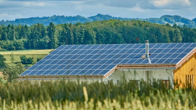 Einfamilienhaus mit Photovoltaikanlage auf dem Dach in ländlicher Landschaft mit Feldern und Wald